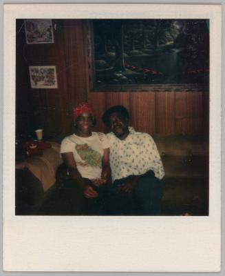 [Woman wearing red bandana sitting on couch with man]
