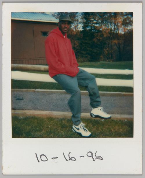 [Man wearing Nike sneakers sitting on fence]
