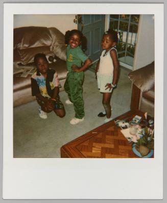 [Three girls posing with hands on hips in living room with front door open]
