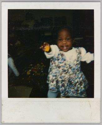 [Toddler in floral dress smiling with hand raised]
