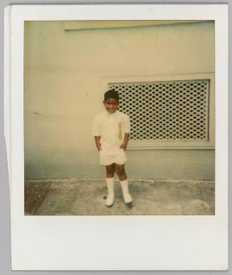 [Child in white knee high boots posing beside wall]
