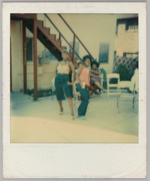 [Two women posing outside with folding chairs]
