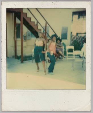 [Two women posing outside with folding chairs]
