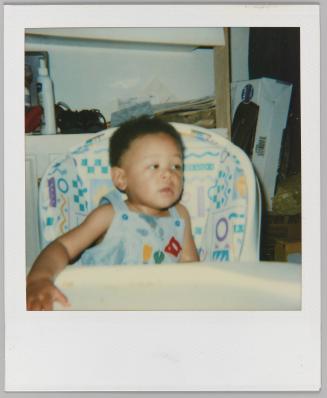 [Toddler in booster seat in overalls]
