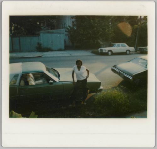 [Woman in white t-shirt posing with car]
