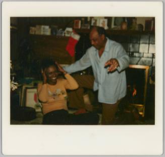 [Man pointing at camera with woman laughing with hands on her head]
