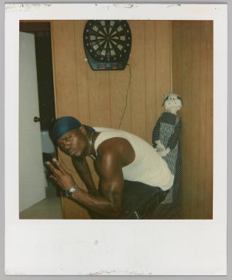 [Man in durag making hand symbol with stuffed toy cow]
