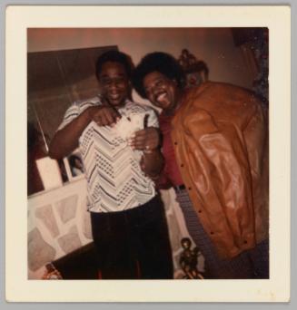 [Two men smile for the camera, holding two American bills]
