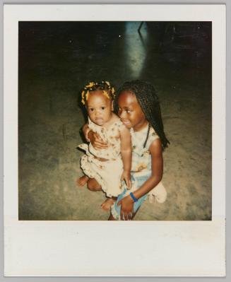 [Toddler leaning against young girl with cornrows]
