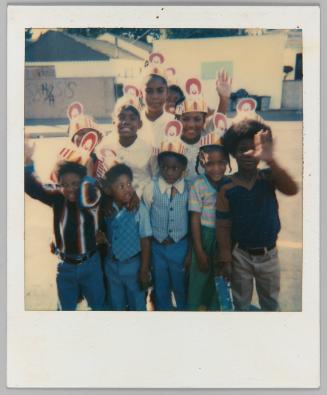[Ten children wearing McDonald's paper hats] 

