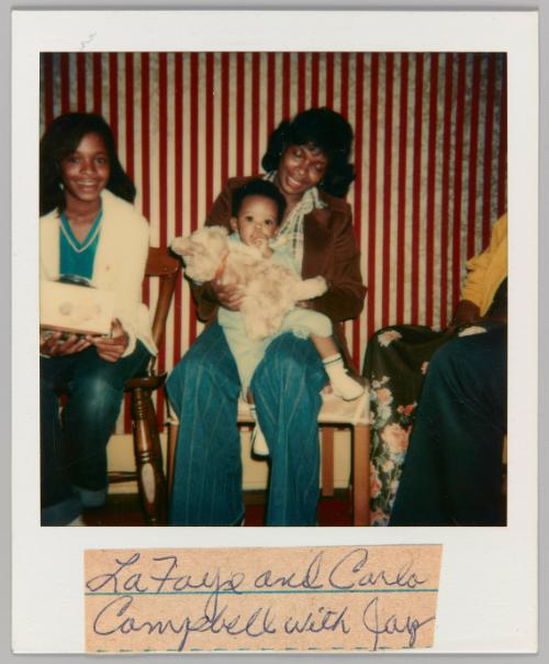 Lafaye and Carlo Campbell with Jay [Woman holding toddler in lap with plush toy]
