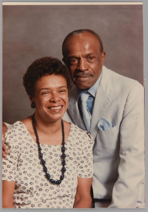 Frances + Richard Edmonds July 1989 Mother + Dad [Portrait of man in a blue suit with his arm around a woman sitting down wearing a bead necklace]