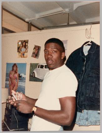 [Man holding chord with poster of woman in bikini in background]
