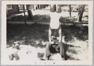 [Young woman balancing upside-down as young man holds her up]
