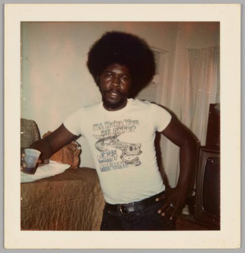 [Man standing inside with one hand on hip and other hand holding plastic cup, he is wearing a t-shirt that reads "I'll make you an offer you can't refuse"]