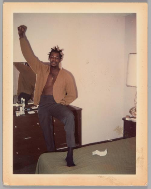 Johnnie Married 1970 [Man with one foot stepped up onto bed and one arm raised with his hand in a fist, dresser with mirror behind him]