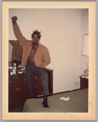 Johnnie Married 1970 [Man with one foot stepped up onto bed and one arm raised with his hand in a fist, dresser with mirror behind him]