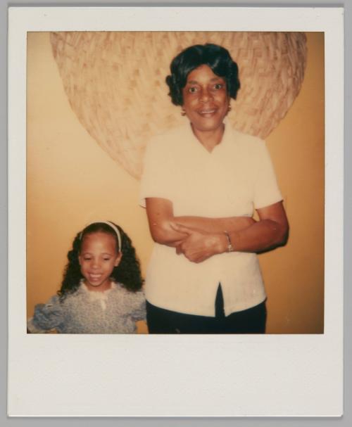 March 20-83 Michelle + Me [Girl wearing headband beside woman with short hair smiling with her arms crossed]