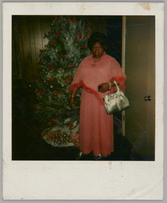 335 [illeg.] 44502 Bonnie + Hall [Woman in pink dress with silver purse standing in front of Christmas tree]
