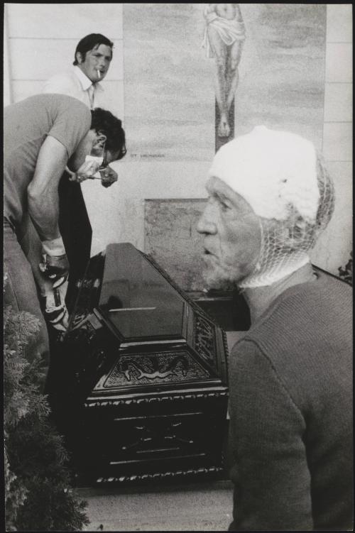 A man with a head injury stands by as two men prepare a coffin for burial in the Osoppo cemetery after the Friuli earthquake in 1976