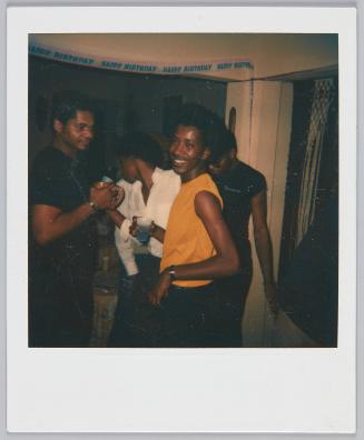 [Young man in yellow tank top holding a drink in hand]