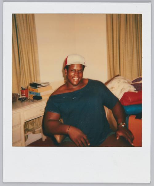 [Man wearing red and white baseball cap and navy blue shirt smiling]