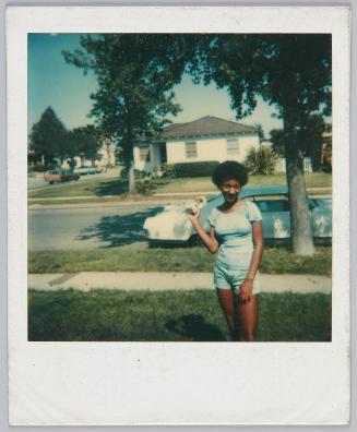 [Young woman in blue shorts and top posing on lawn]
