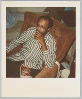 [Older man wearing glasses sitting on brown textured recliner]