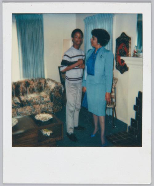 [Women in blue pencil skirt and matching blazer looking at adolescent boy standing next to her]