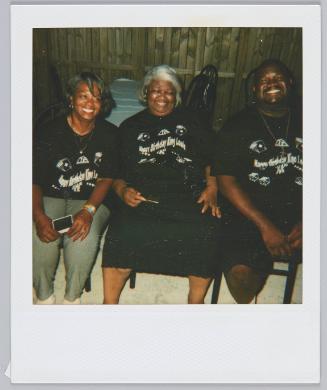 [Two elderly women and man sitting in backyard wearing matching "Happy Birthday King Louie" tshirts]