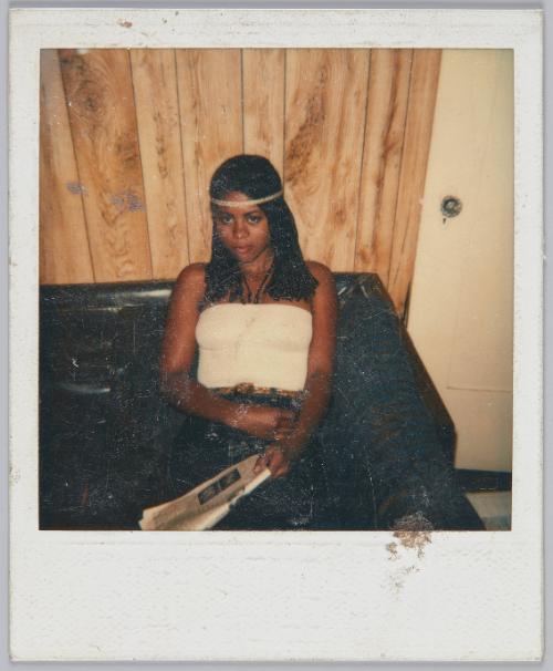 [Young woman sitting on brown leather couch wearing a braid headband]