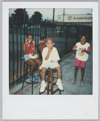 [Three children sitting on wooden stools outdoors, little girl on right wearing a Winnie the Pooh tshirt]