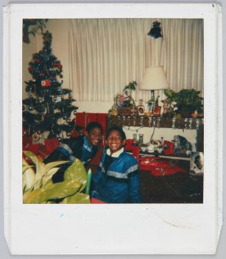 [Two boys smiling in matching windbreakers, Christmas tree and decorations surrounding them]