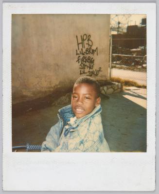 [Little boy in acid wash denim jacket with a faint smile]