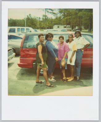 [Group of five women posing with red van behind them]