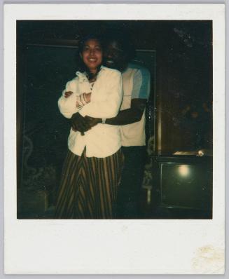 [Couple posing, man standing behind woman with his arms around her]