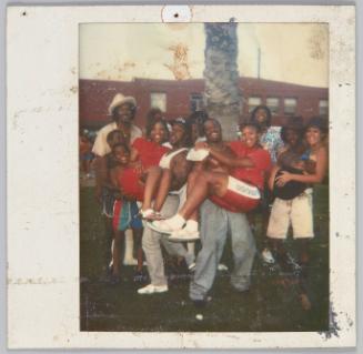 [Large group posing, three men in front row holding three women in their arms]