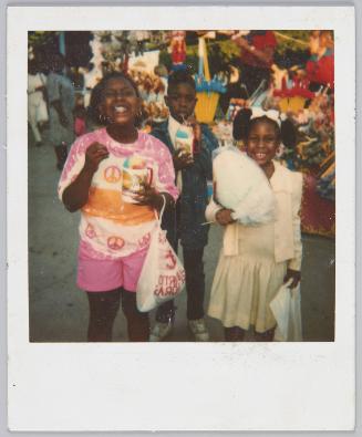[Two girls and a boy eating snowcones and cotton candy at carnival]