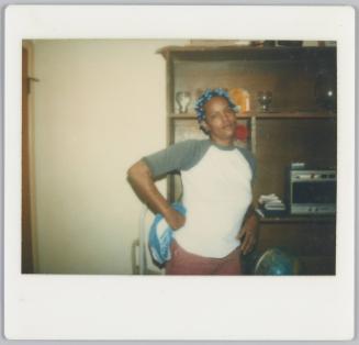 [Woman standing with hands on hips wearing blue curlers in hair]
