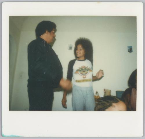 [Woman smiling at man to the left of her, one of her hands is raised at her hip]
