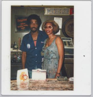 [Man and woman behind bar, sign on back wall 'Michelob']

