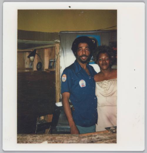[Man and woman behind bar, woman is wearing a strapless white dress]

