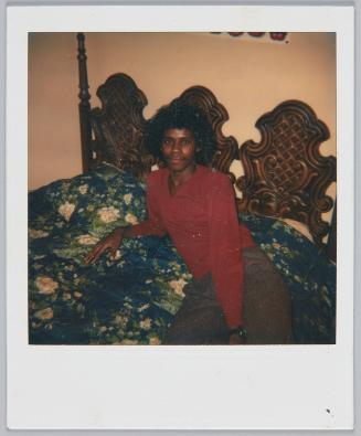 [Young man laying on floral bedspread, wooden headboard]
