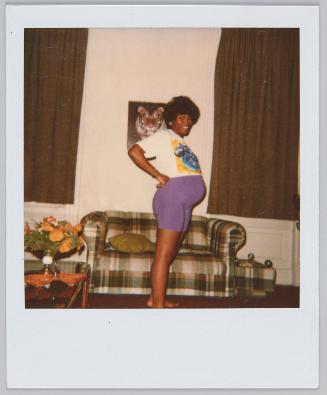 [Pregnant woman standing with hands on hips, image of tiger hung on wall behind her]
