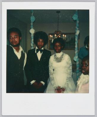 [Bride and groom standing together with blue decorations in background]
