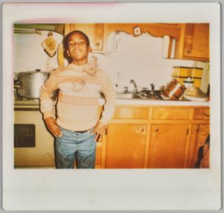 [Boy in striped top standing in front of kitchen sink with his hands on hips]