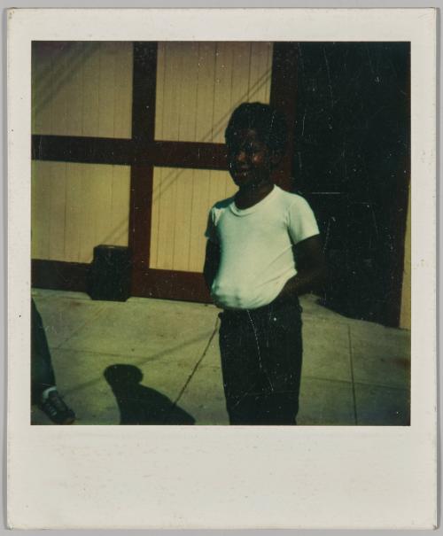 [Boy in white t-shirt standing with his hands under his shirt, his hands are together and pressed against the shirt]