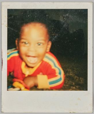 [Close-up of smiling toddler in red shirt with yellow and blue stripes]