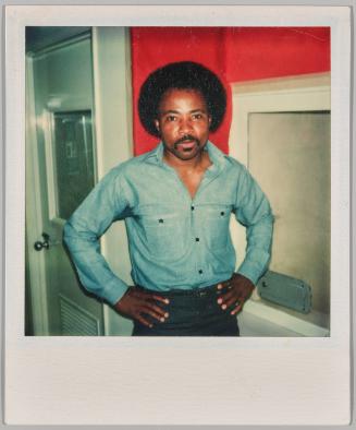 Oct 31 1976 [Man in denim shirt standing with hands on hips in red room]