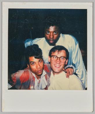 [Three men posing together, man on left has a pompadour hairstyle]
